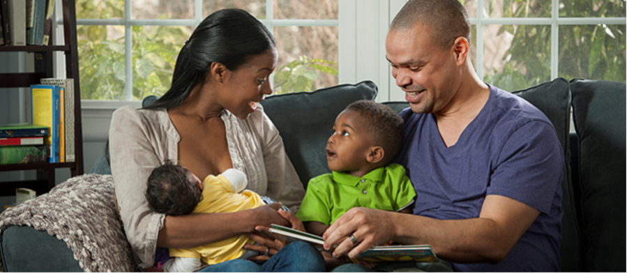 Black/African American baby and parents looking at book