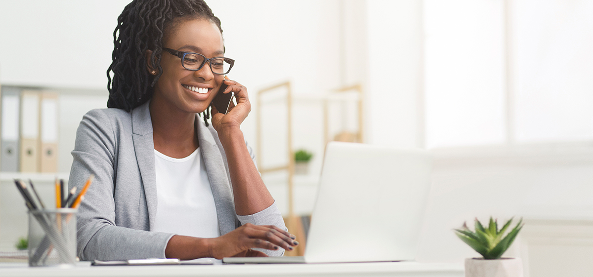 Young Black female office worker at desk with laptop computer